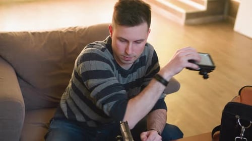 Person Reaching for Equipment Bag on Table While Sitting on Couch