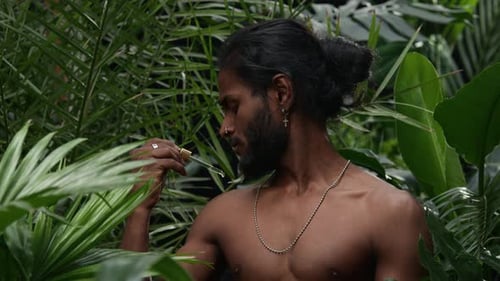 Homem aplicando soro no ombro entre uma exuberante vegetação tropical