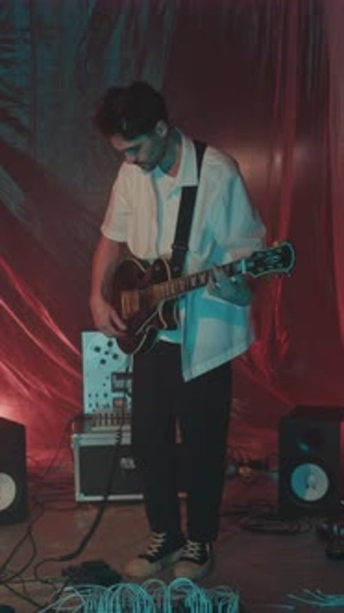 Musician Adjusting Electric Guitar in Neon Studio