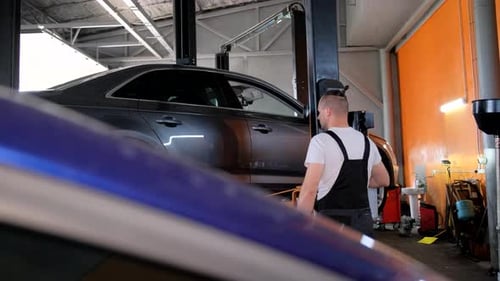 Mechanic Repairing a Vehicle in the Garage Working on Tires and Cars Hood