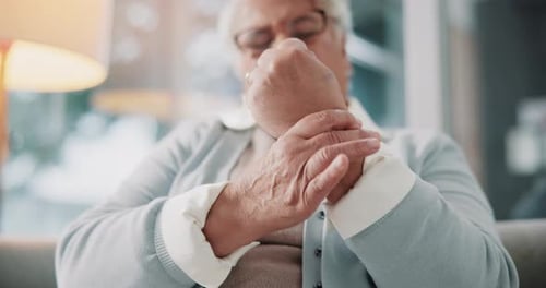 Elderly woman, hands and sofa with arthritis, ache or joint pain from fibromyalgia