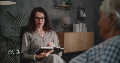 Una psicóloga toma notas en un cuaderno durante la consulta con un antiguo cliente