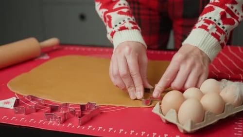 Woman Cutting Christmas Cookies From Dough on Red Mat