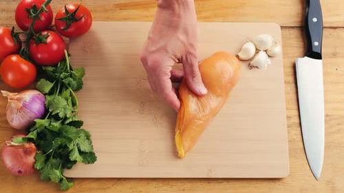 Man Slicing Raw Turkey or Chicken Meat Fillet on Oak Cutting Board Closeup Cooking with Knife on