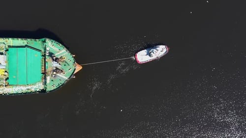 Top down view of a tugboat pulling a cargo ship in port of Varna, Bulgaria. Logistics and transport