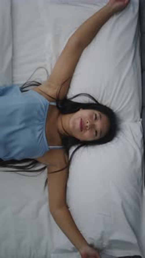 Young Woman Falls Into Bed With Arms Outstretched Smiling Enjoying Moment