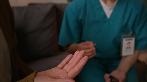 Elderly Woman Using Lancing Device, Nurse Taking Blood Sample for Glucose Meter