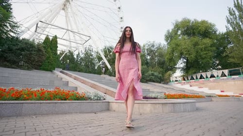 Attractive Woman in Pink Dress and Glasses Smiles and Walks in City Center