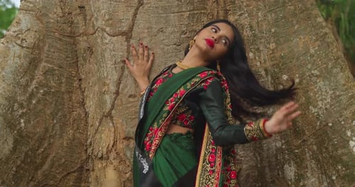 Wearing traditional Indian clothes, a young girl enjoys her day at a tropical park in the Caribbean.