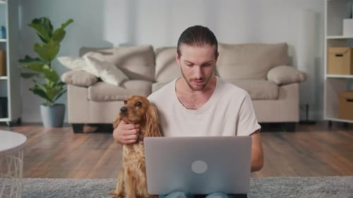Fluffy Coworker Cozy Balance Man Works on Laptop and Plays With His Dog