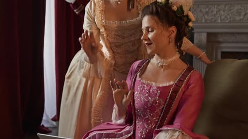 Actresses in 18th Century Costumes Browsing Internet on Laptop on Drama Set