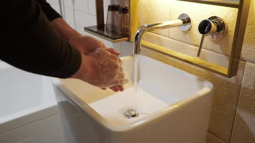Man Washing Hands With Water And Soap In Bathroom