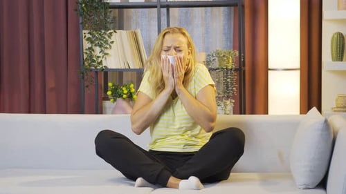 Mujer tapándose la boca y la nariz mientras tose.