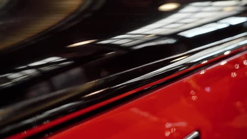 Dolly shot of glossy polished surface of vintage car painted in black and red.