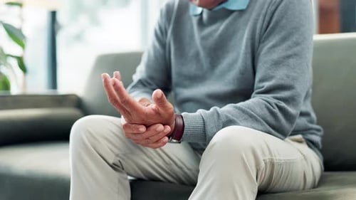 Hand pain, arthritis and couch with elderly person with osteoporosis and stress in retirement home