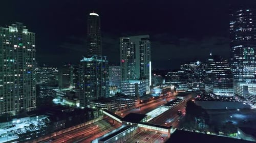 Stunning lighting Skyline of Atlanta City at night. Travelling vehicles on underpass highway. Aerial