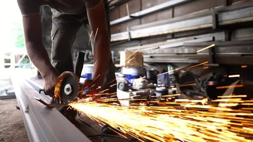 Male Hands of Young Craftsman Cuts Iron Using Electric Grind Wheel at Workshop Arms of Professional