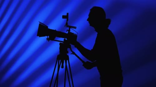 Silhouette of a Cameraman Filming Against Blue Background