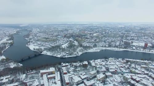 View of the big city with river floating through it on snowy winter day.