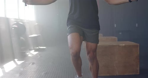 Jumping rope, man exercising in gym wearing tank top and shorts