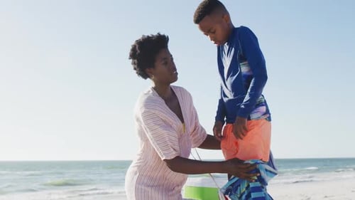 Video of happy african american mother covering son on beach