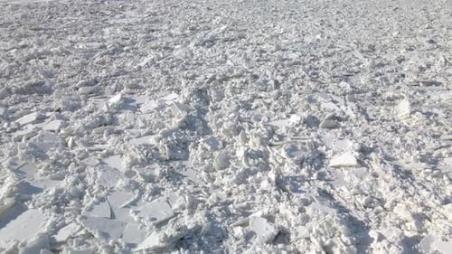 Aerial shot of the cracked ice tiles covering the great river during strong winter in northern Europ