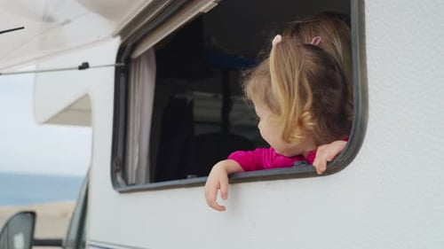 Cheerful Mother and Daughter Look Out of the Camper Window at Nature Family Holidays