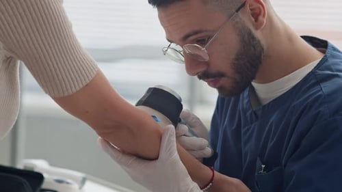 Young Middle Eastern Male Doctor Using Dermatoscope Examining Skin