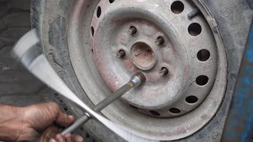 Hands replace tires on wheels with steel tools