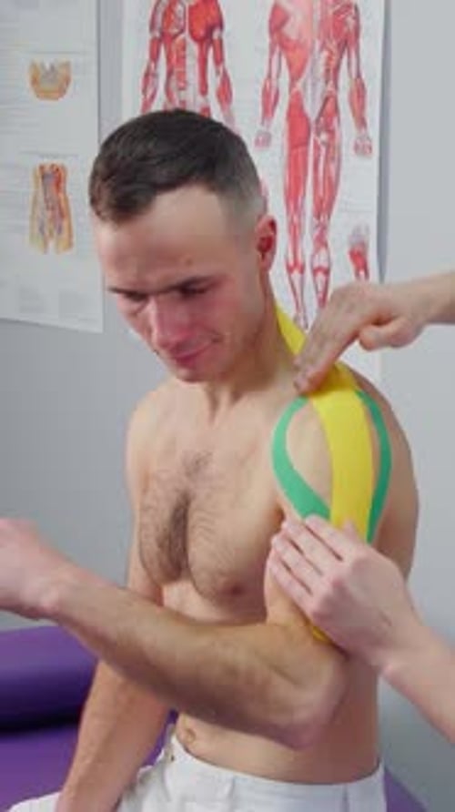 Physiotherapist Makes Kinesio Tapes on Shoulder of an Athlete with an Injury A Doctor in Clinic