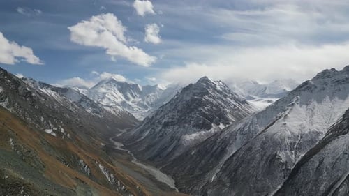 Majestuoso paisaje montañoso que muestra picos nevados y un río sinuoso mientras la cámara se desplaza