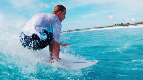 Teen boy surfer takes off and rides the ocean wave in tropical Maldives