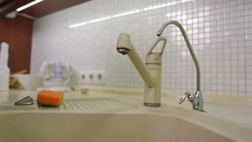 Nahaufnahme Wasser tropft aus einem Wasserhahn, der in der heimischen Küche nicht vollständig geschlossen ist