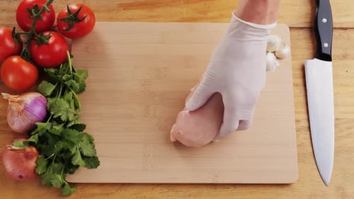 Man Slicing Raw Turkey or Chicken Meat Fillet on Oak Cutting Board Closeup Cooking with Knife on