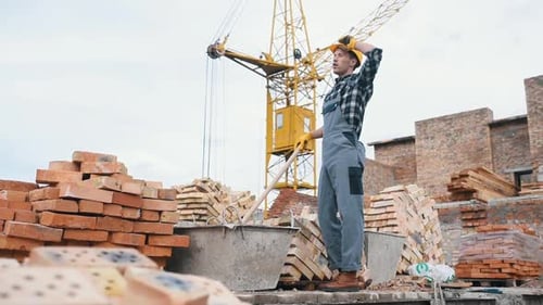 Uses shovel. Construction worker in uniform and safety equipment have job on building