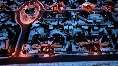 Aerial view of a snowy street with houses. Night lights and Christmas decorations on a cold winter n