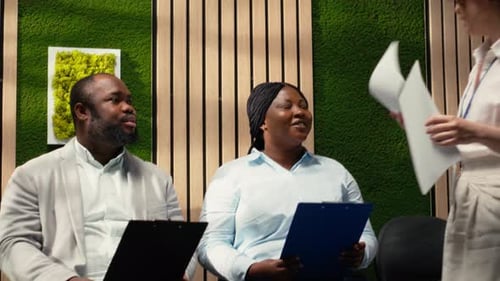 Black Candidates in a Hallway Receive Files to Fill in While They Wait