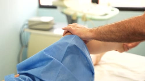 Male physiotherapist bending knee of patient in clinic. Closeup, cropped shot
