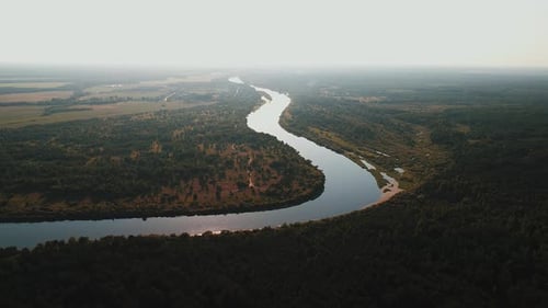 Aerial View of River Bend Flowing Through Valley Among Meadows and Forests with Slight Haze on