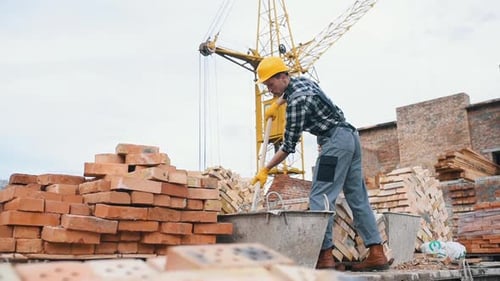 Uses shovel. Construction worker in uniform and safety equipment have job on building