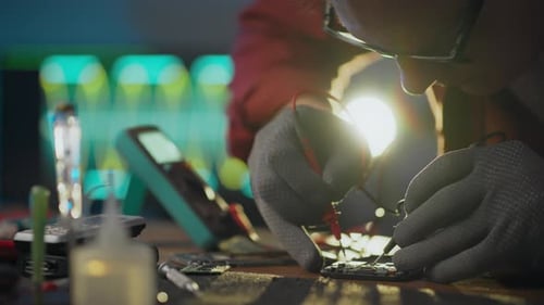 An electrician uses diagnostics on motherboard components in an electrical assembly shop. An