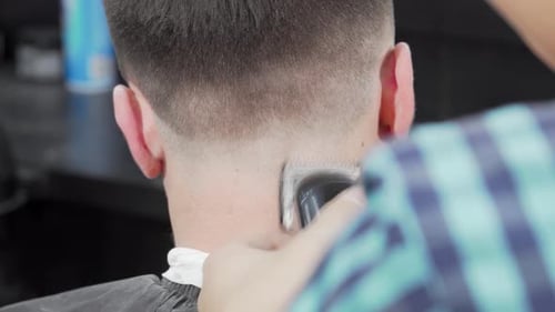 Dynamic Rear View of a Barber Skillfully Using a Clipper to Craft a Stylish Haircut for a Male