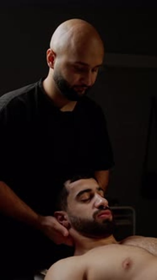 Professional Physiotherapist Carefully Manipulates Patient's Neck Against Dark Background Providing