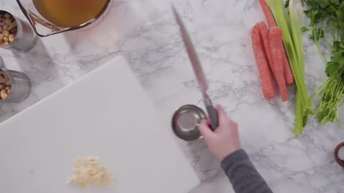 Cutting Vegetables on a White Cutting Board to Cook Vegetarian White Bean Soup