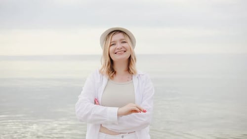 Portrait of a Smiling Blonde Woman Enjoying Her Vacation on the Beach Wearing a Stylish White Hat