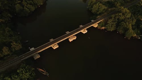 Drone aerial view of narrow gauge railway bridge over waterway during soft evening sunlight in Asia