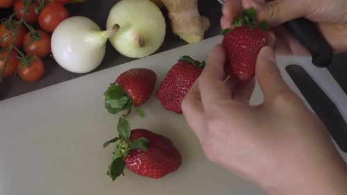 Woman's Hand And Sharp Knife Cutting The Red Strawberry On The Chopping Board. - close up shot
