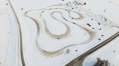 Panoramic drone shot around rally cars driving on a ice track, sunny, winter day