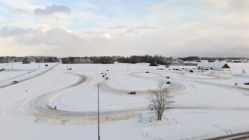 Aerial view rising around cars driving on a rural ice track, winter day