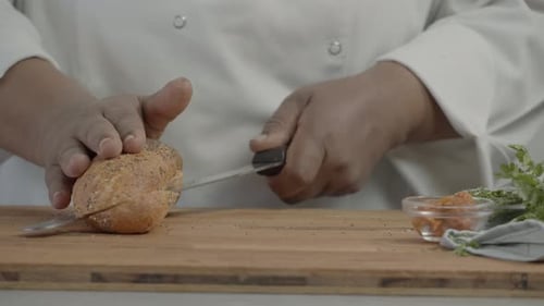 close up of chef's hand cutting bread. man cuts fresh bread with a knife on a wooden cutting board.